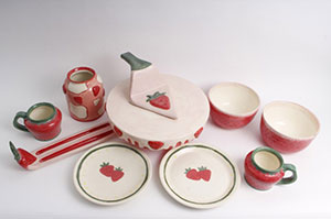 a photo of several pieces of pottery in white and red with green stripes and painted strawberries