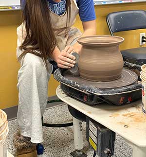 a photo of a teenager working at the pottery wheel