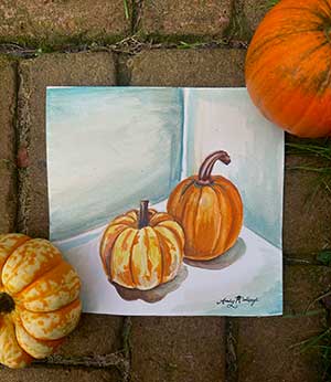 a watercolor painting of two pumpkins plus two actual pumpkins