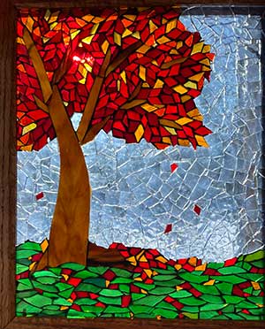 a glass mosaic of a tree with red and orange leaves