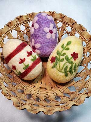 three needle felted Easter eggs in a basket