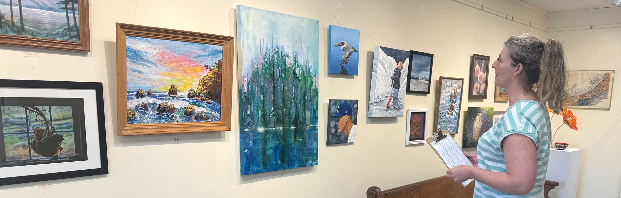 a photo showing the judge for the 2025 Sunday Artist Show looking over the exhibition