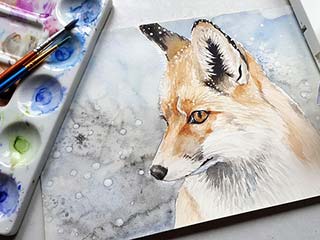 image of a watercolor painting of a fox along with watercolors and watercolor brushes