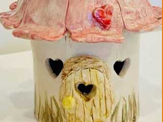 a ceramic fairy house with heart-shaped windows