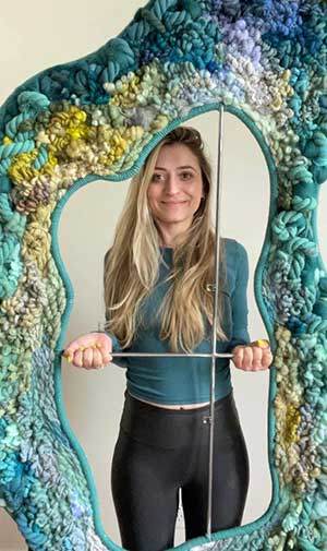 Alison Altafi surrounded by one of her fiber arts creations